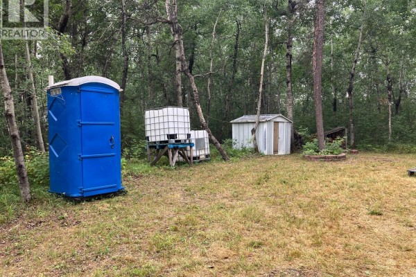 Blue porta-potty, stacked white water tanks, and a small white shed situated in a clearing amongst trees. - Lot 3 - Station Lane, In Rm Of Nipawin, Nipawin Rm No  487