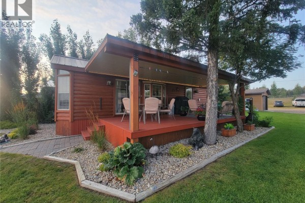 Red wooden stairs lead up to a covered deck with outdoor furniture on a mobile home. - Lot 3 Lakeshore Drive, Eye Hill Rm No  382