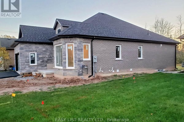 Rear exterior of a grey stone and brick house with a bay window and construction materials on the lawn. - Lot 31 - 201 Hetram Court, Fort Erie