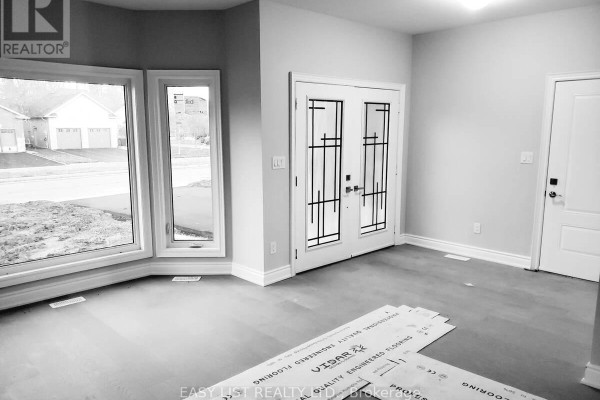 Interior view of an unfinished room with large bay windows, double doors, and a light grey color scheme. - Lot 31 - 201 Hetram Court, Fort Erie