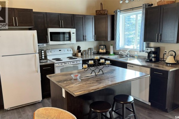 Kitchen with dark cabinets, white appliances, a large island, and a window overlooking trees. - Lot 4 Block 4 Sturgeon Lake West, Sturgeon Lake