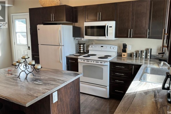 Kitchen with dark cabinets, white appliances, a white stove, and a marble-patterned island. - Lot 4 Block 4 Sturgeon Lake West, Sturgeon Lake