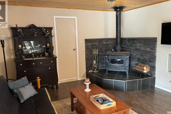 Living room with a wood-burning stove on a stone hearth, a dark dresser, and a couch. - Lot 4 Block 4 Sturgeon Lake West, Sturgeon Lake