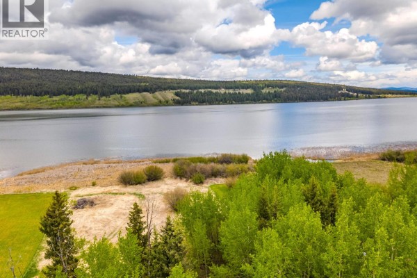 Aerial view showing a lake, rural road, scattered homes, and surrounding evergreen and deciduous forests. - Lot 4 Hunt Road, 100 Mile House