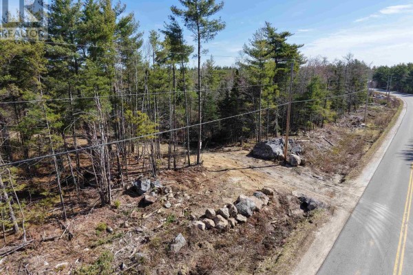 View of a wooded lot with cleared area, rocks, and utility poles bordering a road. - Lot 4 Welshtown, Welshtown
