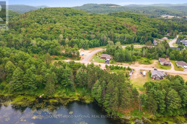Aerial view of rolling hills covered in trees, a lake, and scattered houses. - Lot 48 Lakeview Parkway, Madawaska Valley