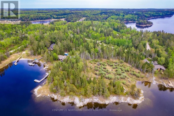 Aerial view of a clearing with low green bushes and surrounding pine trees on a rocky point by the water. - Lot 5-21 Eagle Crescent, Kenora