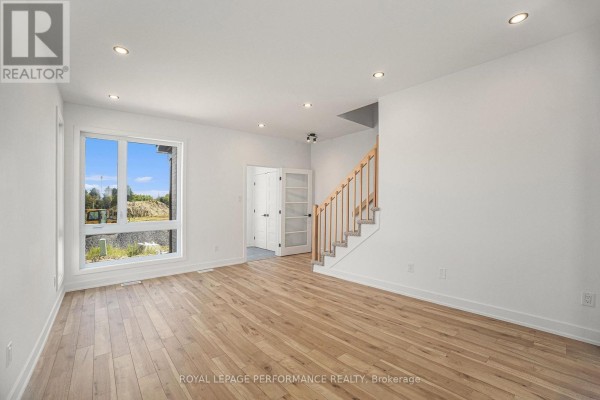 Living room with light wood floors, white walls, a large window, and glass-paneled doors to a hallway. - Lot 5 Juniper Street, The Nation