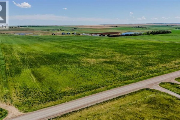 Aerial view of green fields alongside a paved road with a distant farm in the background. - Lot 5, Magrath