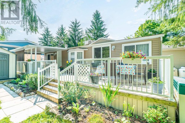 Close-up of the mobile home with porch, flower pots, and landscaped garden. - Lot 53 - 2152 Hwy 36, Kawartha Lakes