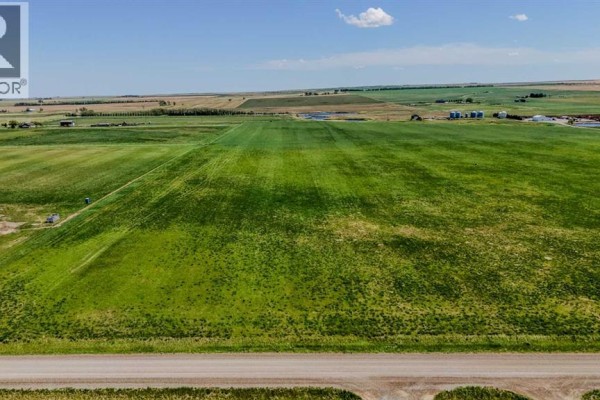 Wide view of a lush green field with farm structures visible on the horizon. - Lot 6, Magrath