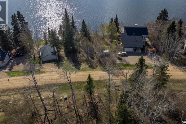 Aerial view of houses nestled among trees on a slope leading down to a sparkling lake. - Lot 7 - Sunset Cres, Cowan Lake