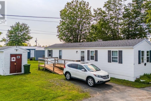 Side view of beige manufactured home with wooden deck and dark sedan. - Lot 7 & 8 Dalton Court, Bible Hill