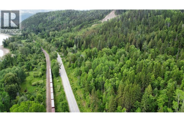 Aerial view of a forest, train tracks, and a road adjacent to a body of water. - Lot 8 Arrow Lakes Drive, Castlegar