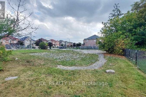 View of the lot with scattered gravel, adjacent to residential homes. - Lot C - 0 Melbourne Drive, Richmond Hill