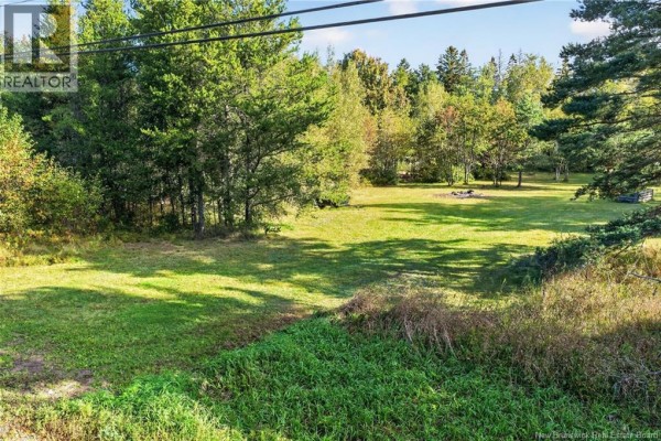 Open green lawn with a circular fire pit and stacked wood. - Lot De La Breche Road, Grand Barachois