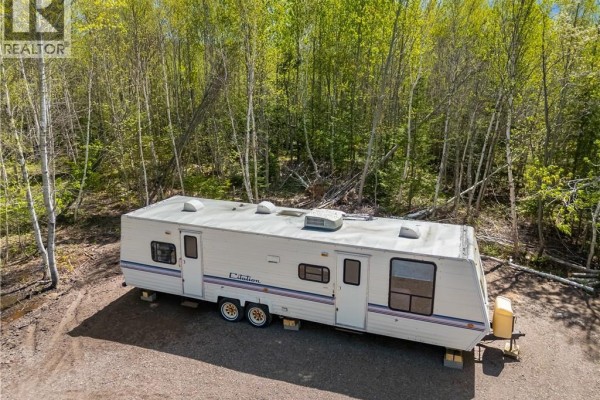 Close-up aerial view of a white travel trailer parked on a gravel pad. - Lot Duguay Point Road, Shemogue