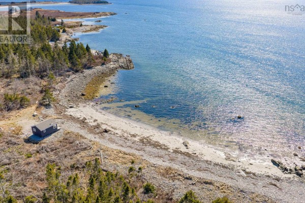 Aerial view of rocky coastline with calm green water and scattered trees along the shore. - Lot Mb-1 Rockland Road, East Side Of Ragged Island