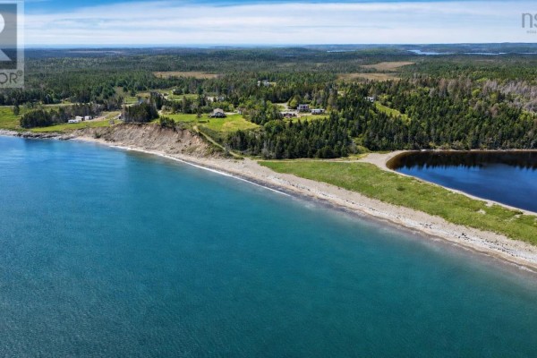 Aerial view of a coastal property with ocean, beach, trees, and scattered houses. - Lot No 327 Highway, Gabarus