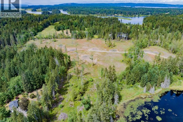Aerial view of a gravel road winding through a sparsely treed lot with clearings. - Lot Quennell Rd, Nanaimo