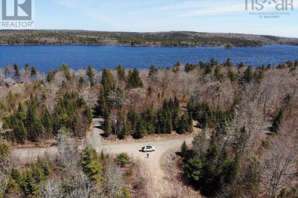 Aerial view of a wooded area with a road, a white SUV, two people, and a blue lake beyond. - Lot R-11 Kill Dog Cove Road, Parkdale