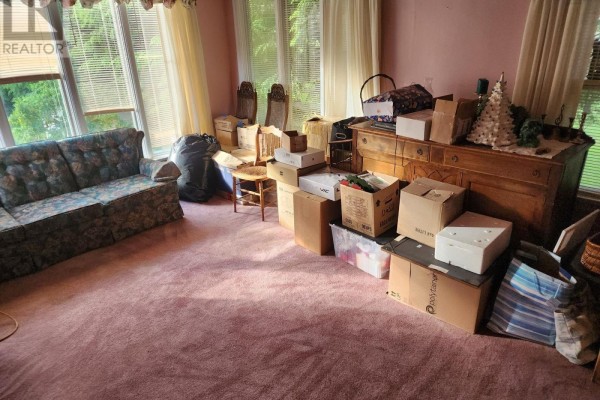 Living room filled with boxes, featuring a floral couch and large windows. - Lots 3&10, 70 Victoria Road, Lunenburg