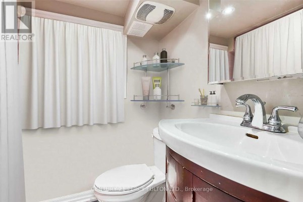 A compact bathroom with a white toilet, sink, and dark wood vanity. - Lower - 10 Muriel Avenue, Toronto