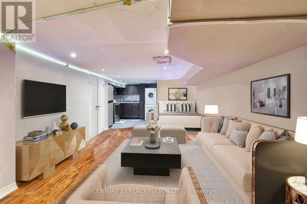 A large living space with a sectional sofa, coffee table, and entertainment unit. - Lower - 10 Muriel Avenue, Toronto