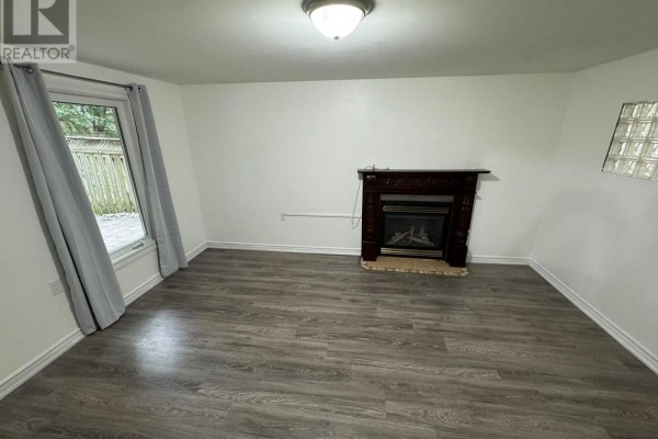 Living room with gray laminate flooring, fireplace with dark wood mantle, and walk-out patio door. - Lower - 1107 Beaver Valley Crescent, Oshawa