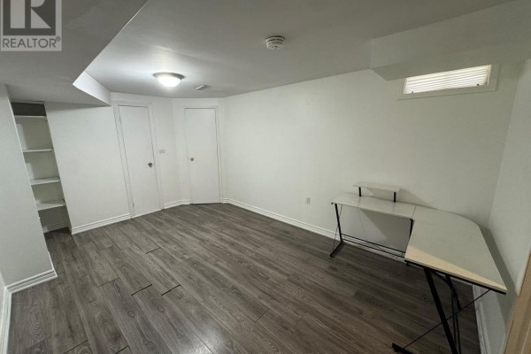 Room with gray laminate flooring, l-shaped white desk, and built-in white shelving unit. - Lower - 1107 Beaver Valley Crescent, Oshawa