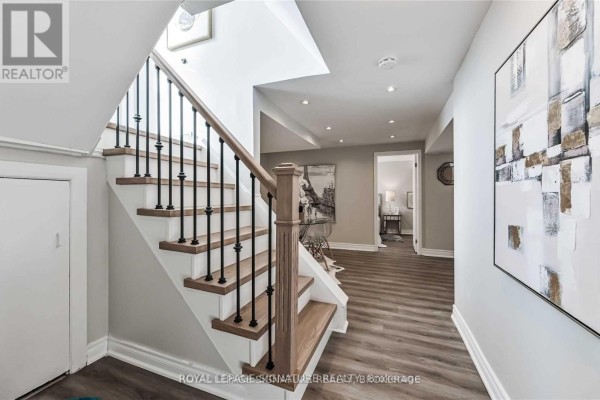 Hallway with wooden staircase, black spindles, and abstract art on the walls. - Lower - 123 Bowman Avenue, Whitby