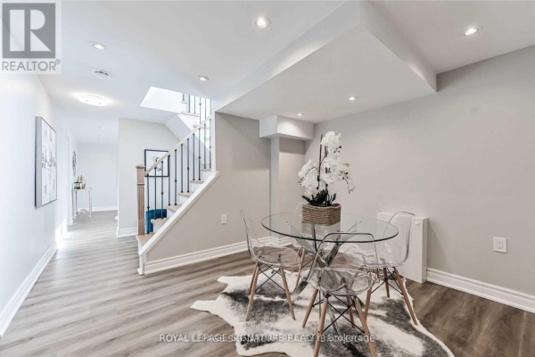 Dining area with glass table, clear chairs, and cowhide rug next to staircase. - Lower - 123 Bowman Avenue, Whitby