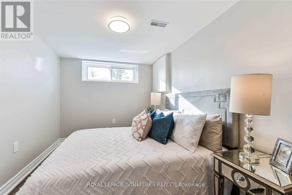 Bedroom with queen bed, grey headboard, and mirrored nightstand. - Lower - 123 Bowman Avenue, Whitby