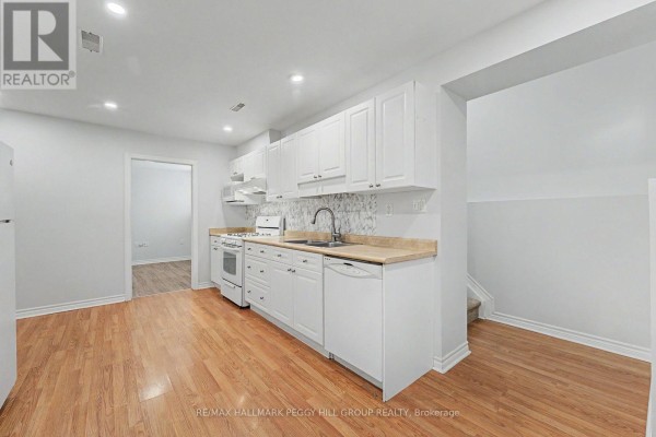 A white kitchen with light wood floors, white cabinets, and a gas stove. - Lower - 148 Livingstone Street E, Barrie