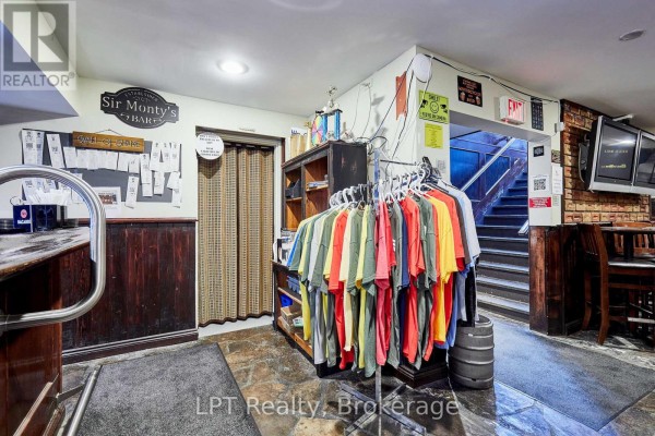 T-shirt display rack near a wooden bar and entrance to a staircase. - Lower - 1540 Highway 2 Highway, Clarington