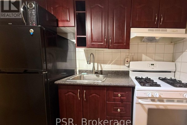 Close-up of a kitchen with dark cherry cabinets, stainless steel sink, white gas stove, and black refrigerator. - Lower - 191 Coxwell Avenue, Toronto