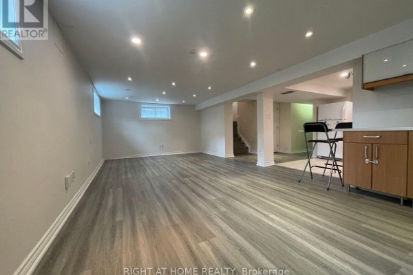 Spacious finished basement with grey wood-look vinyl flooring and recessed lighting. - Lower - 191 Princess Avenue, Toronto