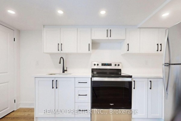 Close-up of a basement kitchen with white cabinets, black hardware, and stainless steel stove. - Lower - 208 Mcroberts Avenue W, Toronto
