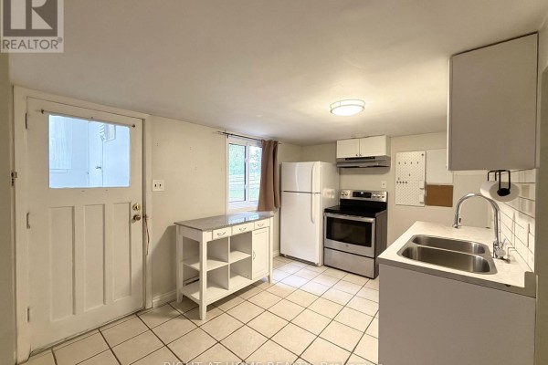 Kitchen with white cabinetry, appliances, white tiled floor, and a door to the exterior. - Lower - 214 Greenwood Avenue, Oshawa