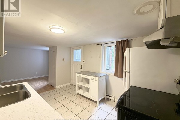 Kitchen area with white cabinets, appliances, and a doorway leading to a living room. - Lower - 214 Greenwood Avenue, Oshawa