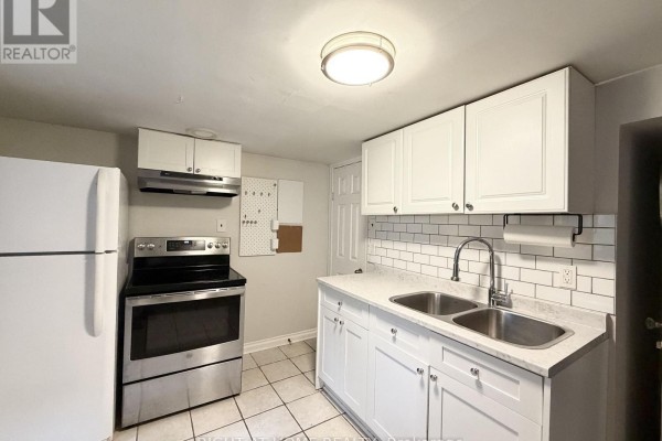 Kitchen with white subway tile backsplash, stainless steel stove, and a double sink. - Lower - 214 Greenwood Avenue, Oshawa