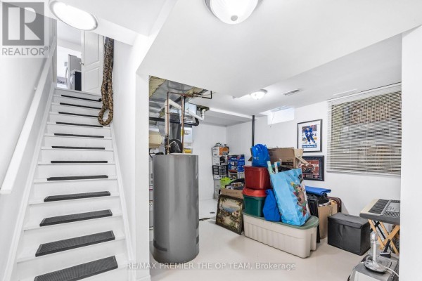 Unfinished basement with a water heater, storage bins, and a staircase. - Lower - 223 Landsbridge Street, Caledon