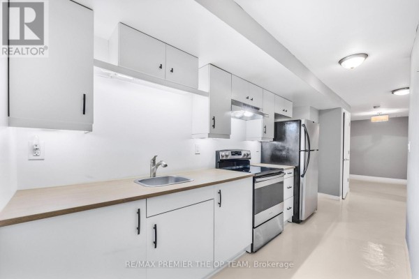 Small kitchen with white cabinets, a stainless steel sink, and appliances. - Lower - 223 Landsbridge Street, Caledon