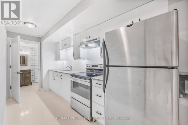 Kitchen area with white cabinets, stainless steel appliances, and a doorway to a bathroom. - Lower - 223 Landsbridge Street, Caledon