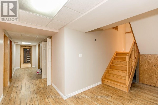 Interior hallway with light wood floors, a wooden staircase, and doors leading to rooms. - Lower - 299 Lakeview Boulevard, Georgina