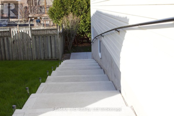 Concrete stairs leading down to a grassy yard with a wooden fence. - Lower - 33 Anderson Street, Woodstock