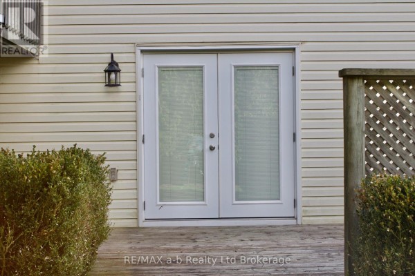 White double doors with blinds set into a beige vinyl-sided building. - Lower - 33 Anderson Street, Woodstock