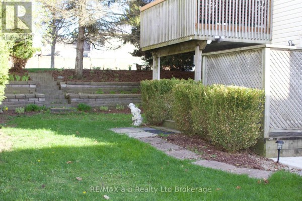Tiered retaining wall and garden beds in a green backyard with trees. - Lower - 33 Anderson Street, Woodstock