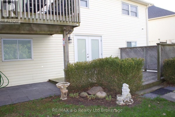 Deck with wooden railing overlooking a backyard with bushes and garden gnomes. - Lower - 33 Anderson Street, Woodstock