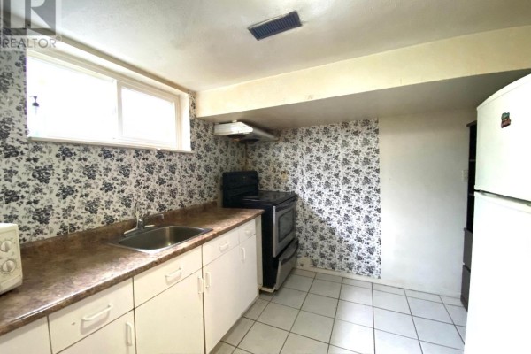 Small basement kitchen with white cabinets, floral wallpaper, and a stove. - Lower - 3320 Grechen Road, Mississauga